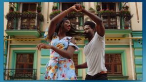 Pareja bailando merengue alegremente en una calle colorida.