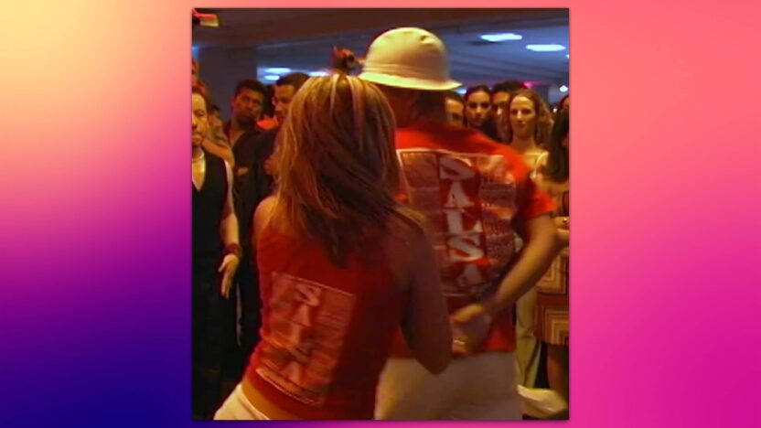 Pareja bailando salsa en una concurrida pista de baile.